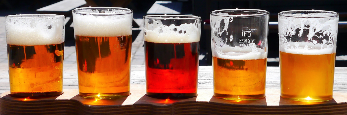 Five samples of draft beer lined up on a wooden bar