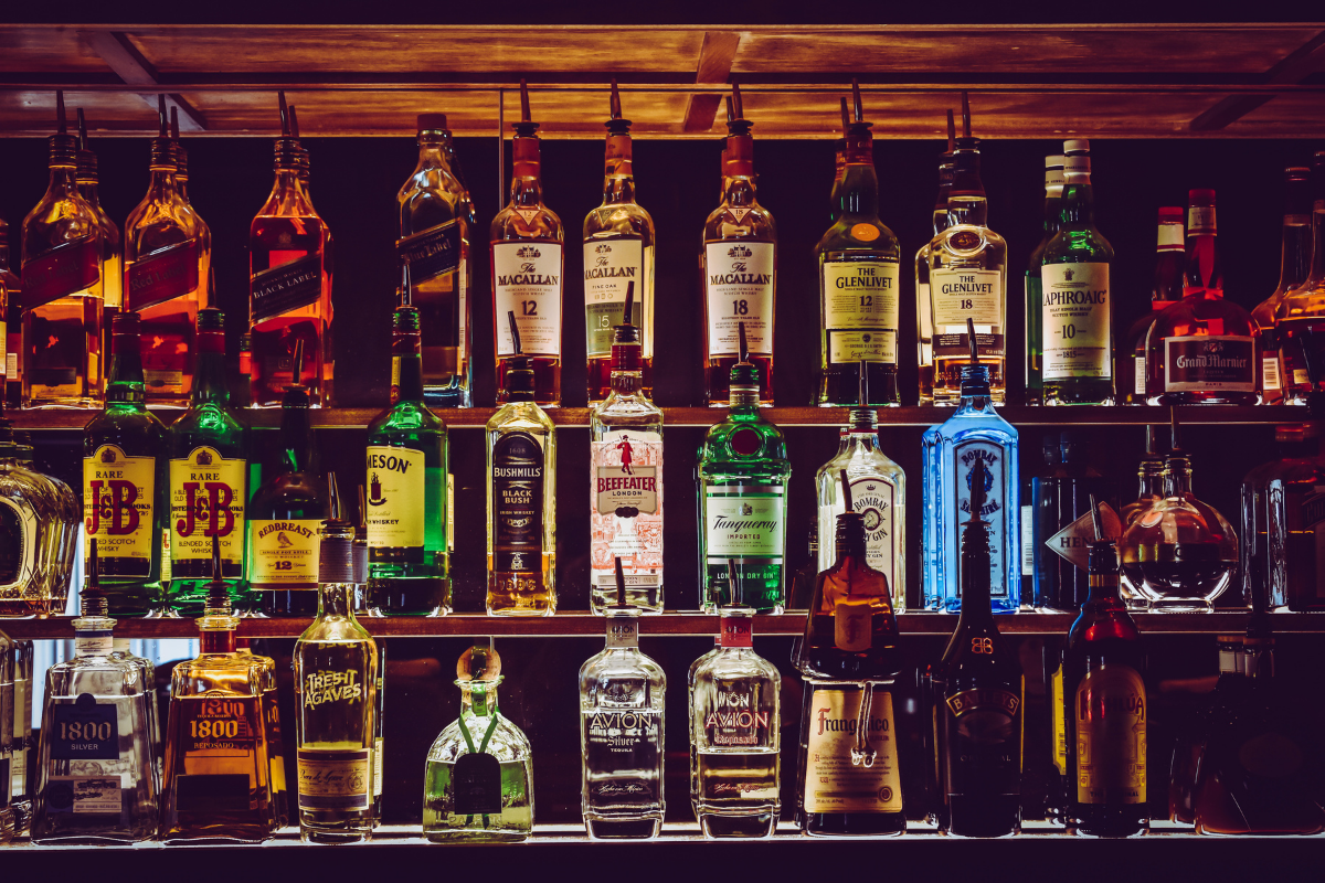 Wooden bar with various liquor bottles with lighting behind making the bottles light up